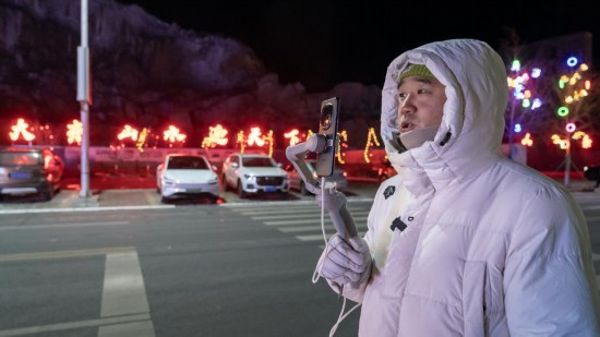 在吉林市阿什哈達霧凇觀景帶，霧凇播報員正在直播。新華社記者 李典 攝