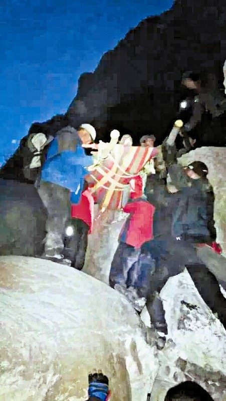 救援隊(duì)員用自制的簡易擔(dān)架抬傷者。