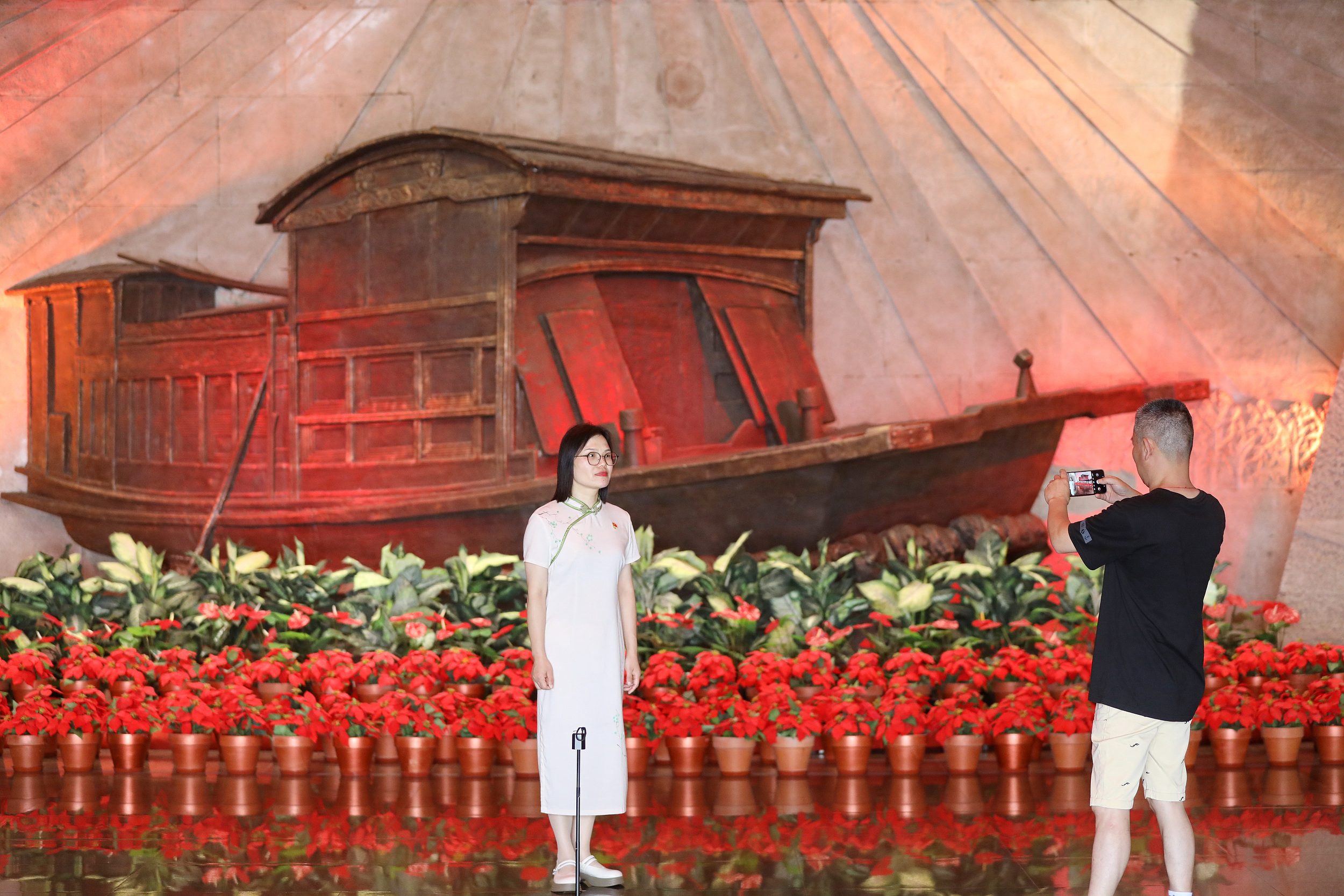 2025年6月24日，浙江嘉興，游客在南湖革命紀(jì)念館與紅船雕塑合影。（圖片來源：視覺中國(guó)）